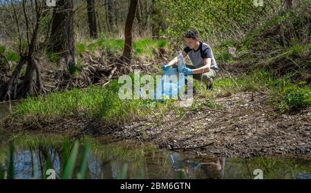 Reinigung von Plastikmüll am Flussufer durch einen Freiwilligen. Der Natur und dem Umweltschutz zu helfen Stockfoto