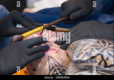 Mann, der sein Gesicht nach der polynesischen Methode tätowiert hat. Bei dieser Methode wird ein Kamm von Nadeln mit dem Stick von Hand auf die Haut eingeklopft. The Lond Stockfoto