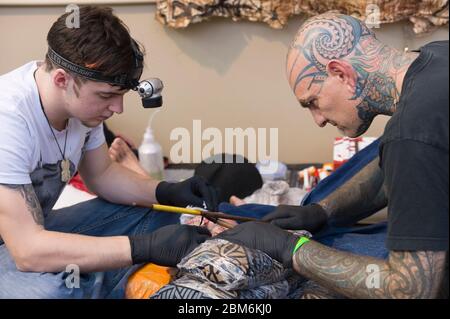 Mann, der sein Gesicht nach der polynesischen Methode tätowiert hat. Bei dieser Methode wird ein Kamm von Nadeln mit dem Stick von Hand auf die Haut eingeklopft. The Lond Stockfoto