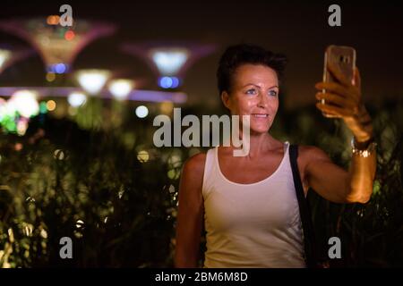 Glücklich reifen schöne touristische Frau, die Selfie in der Stadt bei Nacht Stockfoto