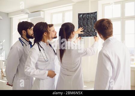 Eine Gruppe von medizinischen Mitarbeitern sieht sich ein Bild von Xray an, das an einem Fenster in einem Krankenhaus steht. Stockfoto