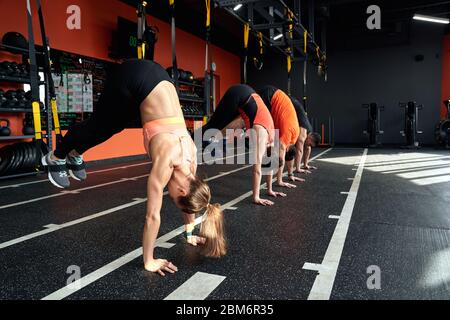 Sportlicher Lifestyle. Junge Leute machen Hecht TRX Übung im Fitnessstudio Stockfoto