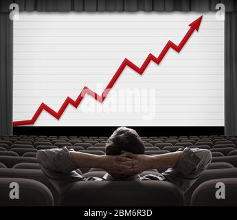 Mann sitzt und schaut mit wachsendem Finanzdiagramm auf den Bildschirm Stockfoto