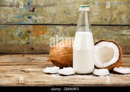 Konzept Bild von Kokosnüssen mit Flasche Milch auf Holz Hintergrund mit Kopierraum Stockfoto