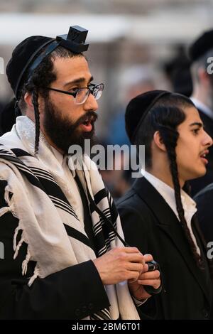 Israel, Jerusalem, Westmauer, ein Haredischer jüdischer Mann im traditionellen Tallit - Gebetsschal - und Tellifin oder Phylaktriechgesänge in Anbetung an der Westmauer des Tempelbergs im jüdischen Viertel der Altstadt. Die Altstadt von Jerusalem und ihre Mauern - UNESCO-Weltkulturerbe. Stockfoto