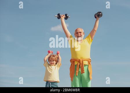 Wie Sport. Senior Mann Training im Rehabilitationszentrum. Sport zu treiben ist kostenlos. Sportler Großvater und gesundes Kind mit Hantel Übung Stockfoto