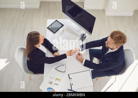 Erfolgreiches Gespräch. Handschlag von Geschäftsleuten Recruiter am Tisch im Büro. Mann und Frau schütteln Hände Draufsicht. Stockfoto