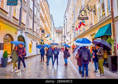 SALZBURG, ÖSTERREICH - 1. MÄRZ 2019: Die Aktivität während des Regentags in der Getreidegasse, der beliebten Einkaufsstraße der Altstadt, am 1. März in Salzburg Stockfoto