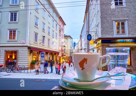 SALZBURG, ÖSTERREICH - 1. MÄRZ 2019: Die angenehme Nachtruhe mit einer Tasse traditionellen Kaffee Melange in einem der Freiluftcafés am Anfang Stockfoto