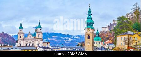 Der Hang des Monchsberg mit Blick auf die Dächer der Altstadt, barocke Fassade des Salzburger Doms, hoher Glockenturm des Klosters St. Peter und regnerische Wolken, Stockfoto