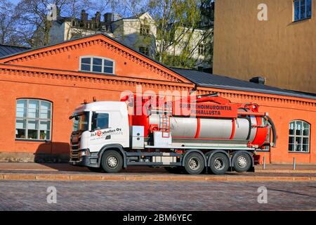 Weißer Scania Vakuum- und Drucktank-LKW von J&J Puhallus Oy, der auf der Straße im Stadtverkehr im Morgenlicht fährt. Helsinki, Finnland. Mai 2020. Stockfoto