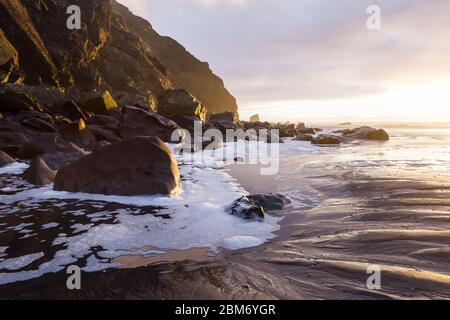 Goldenes Licht, das auf den Felsen am Kap Sebastian reflektiert, während die Sonne unter den Horizont fällt und der Landschaft in den Felsen Helligkeit und Farbe verleiht Stockfoto