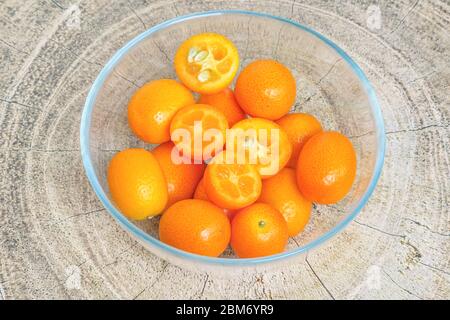 Frische reife Kumquat Früchte in einem Glasteller auf einem Holztisch. Stockfoto