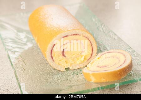Eine geschnittene Arctic Roll gefrorene Wüste mit Gießzucker auf einem Glas Servierteller bestäubt. Stockfoto