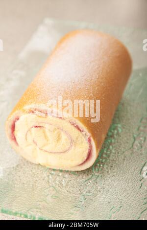 Eine ganze Arctic Roll gefrorene Wüste mit Gießzucker auf einer Glasschale bestäubt. Stockfoto