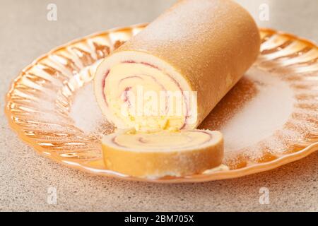 Eine in Scheiben geschnittene Arctic Roll gefrorene Wüste, die mit Gießzucker auf einer Goldplatte bestäubt wurde. Stockfoto