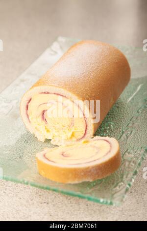Eine geschnittene Arctic Roll gefrorene Wüste mit Gießzucker auf einem Glas Servierteller bestäubt. Stockfoto