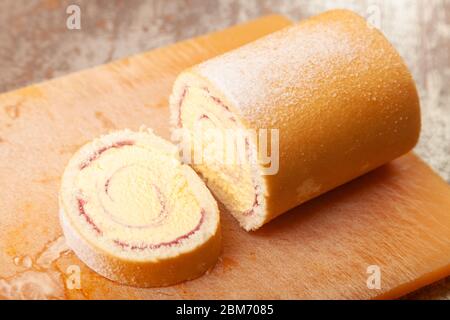 Eine Arctic Roll gefrorene Wüste mit Gießzucker auf einem Kunststoff-Schneidebrett bestäubt. Stockfoto