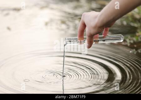 Ein Spezialist Hand zieht Wasser in eine Flasche aus einem Fluss für weitere Forschung im Labor. Prüft den Grad der Wasserverschmutzung. Selektive Fokussierung Stockfoto