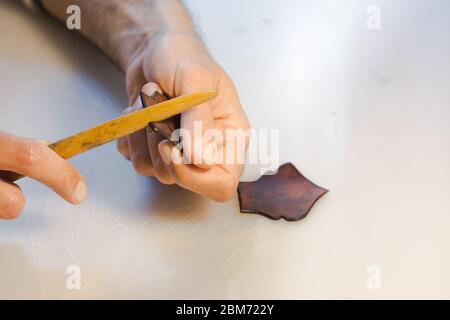 Lederrand Burnishing, Lederrand Finishing von handgefertigten Werkzeugen. Der Prozess der Herstellung einer Ledertasche handgefertigt. Der Handwerker näht ein Leder Stockfoto