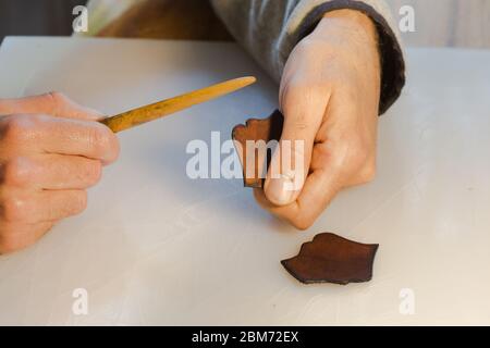 Lederrand Burnishing, Lederrand Finishing von handgefertigten Werkzeugen. Der Prozess der Herstellung einer Ledertasche handgefertigt. Der Handwerker näht ein Leder Stockfoto