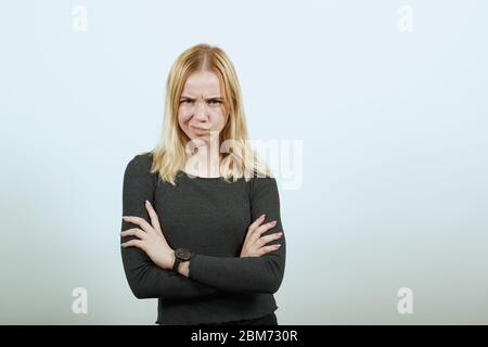 Junge Blonde Frau In Schwarz Pullover Auf Weißem Hintergrund, Verärgert Mädchen Wütend Stockfoto