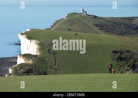 Wanderer in der Nähe von Beachy Fahren Sie auf dem hügeligen South Downs Way in East Sussex und nähern sich dem Belle Tout Leuchtturm auf den Klippen Stockfoto