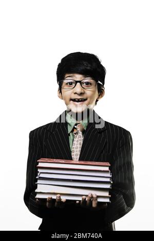 Cute Intelligent Little Boy hält Bücher und trägt eine Brille, lächelnd, während isoliert auf weißem Hintergrund Stockfoto