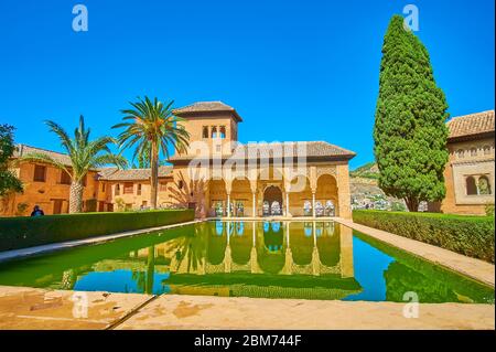 GRANADA, SPANIEN - 25. SEPTEMBER 2019: Die Fassade des Palastes Partal Portikus und Damenturm mit einem Pool des Partal Garten im Vordergrund, Alhambra, auf Stockfoto