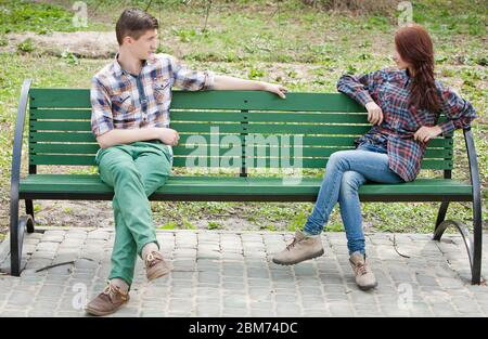 Flirting junges Paar in karierten Hemden auf einer Bank im Park sitzen Stockfoto