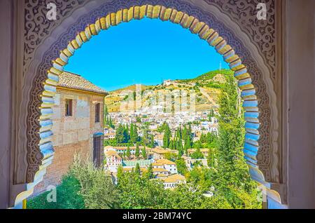 Der Hufeisenbogen des Löwenpalastes der Alhambra eröffnet den Blick auf die hügelige Landschaft von Granada, seine alten Bezirke Albaicin und Sacromonte, Spai Stockfoto