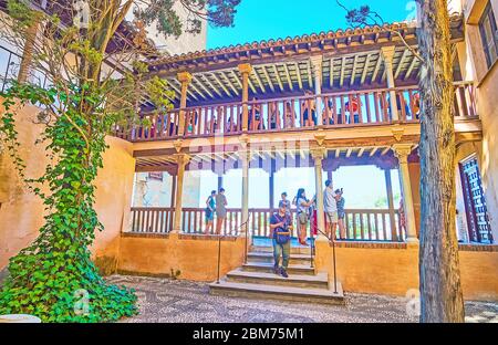 GRANADA, SPANIEN - 25. SEPTEMBER 2019: Die Holzterrasse blickt auf den Innenhof des schmiedeeisernen Grille (Nasridenpalast, Alhambra) mit schattigen Bäumen, am September Stockfoto