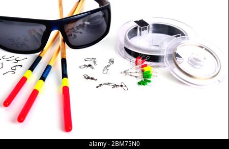 Angelzubehör, blaue Gläser, Schwimmkörper und Angelschnur in der Rolle, Stopper Haken und Drehungen mit Klammern auf weißem Hintergrund, Nahaufnahme, Raum f Stockfoto