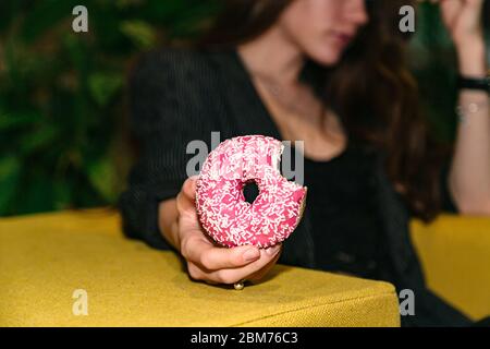 Gebissene Donut mit Streuseln in Frau Hand Nahaufnahme Stockfoto