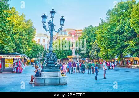 GRANADA, SPANIEN - 25. SEPTEMBER 2019: Die malerische Vintage-Straßenlaterne, dekoriert mit Gripin-Skulpturen, Girlanden und Reliefdekoren in Bib-Rambla squa Stockfoto