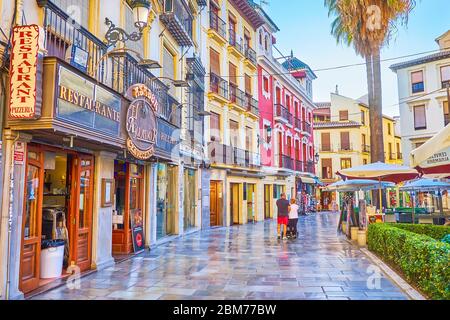 GRANADA, SPANIEN - 25. SEPTEMBER 2019: Spazieren Sie durch die malerische Calle Capuchinas mit historischen Stadthäusern, Restaurants, Cafés, Bars, beschnittenen Büschen und Stockfoto