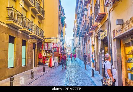 GRANADA, SPANIEN - 25. SEPTEMBER 2019: Genießen Sie die Einkaufsmöglichkeiten, zu Fuß engen Calle San Jeronimo Straße, mit Reihen von historischen Gebäuden und riesigen Kuppel von S Stockfoto