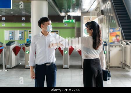 Ellenbogenschlag ist eine neue neue Begrüßung, um die Ausbreitung von Coronavirus zu vermeiden. Zwei asiatische Wirtschaftsfreunde treffen sich in der U-Bahn-Station. Statt mit einer Umarmung zu grüßen Stockfoto