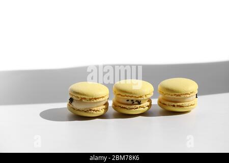 Set von gelben Makronen mit Schatten aus Fenster isoliert auf weißem Hintergrund. Nahtloses Muster. Köstliche gesunde französische Nachspeise. Kreatives, minimales Design Stockfoto