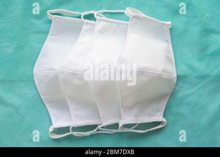 Stapel von hausgemachten Schutz wiederverwendbare antivirale weiße Masken auf grünem Tuch Stockfoto