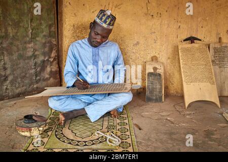 Muslimischer Mann, der korankalligraphie auf einer Holztafel praktiziert. Stockfoto