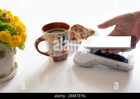 Kontaktlose Bezahlung über Mobiltelefon im Café. Kunden zahlen am POS-Terminal am Schalter im Café. Stockfoto