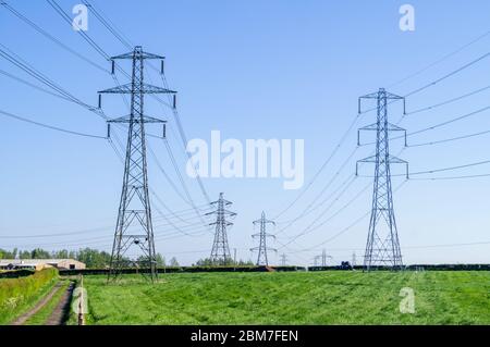 Strommasten in England - Englisch Masten Power Tower Felder Feld grün Gras Verteilung Netz Energie Hochspannung Übertragung Turm Stockfoto