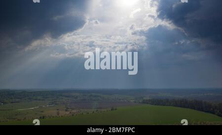 Große Sturmwolken, unter denen es sintflutartigen Regen mit Blitz, über landwirtschaftlichen Feldern. Blick von der Drohne Stockfoto