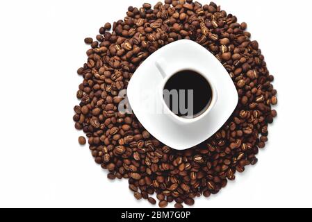Weiße Tasse Kaffee auf einer weißen Untertasse steht auf einem Hügel von Kaffeebohnen auf einem weißen Hintergrund isolieren, Nahaufnahme, Draufsicht Stockfoto