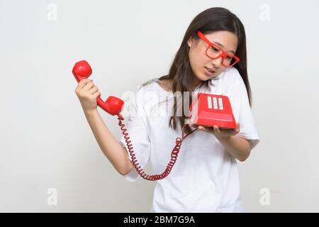 Porträt der jungen asiatischen Nerd Frau im Gespräch auf Handy, während sie altes Telefon Stockfoto