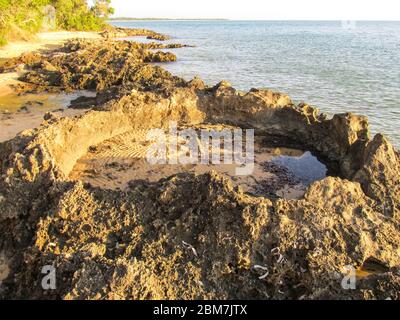 Große Schlaglöcher erodierten am späten Nachmittag im Strandfelsen an der Küste der Insel KaNyaka im Süden Mosambiks Stockfoto