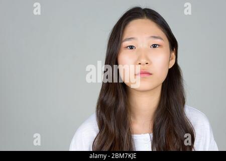 Gesicht einer jungen, schönen asiatischen Frau, die die Kamera betrachtet Stockfoto