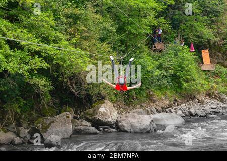 Rize / Türkei - August 06 2019: Rückansicht des kopfüber gleitenden Touristen auf der Zip-Line-Tour im Firtina-Tal. Stockfoto