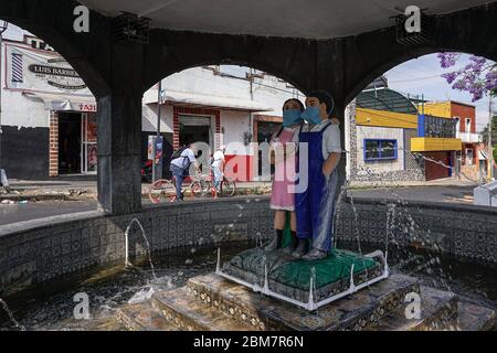 Im April erschienen Masken auf den Statuen der Kinder in Fuente de los Muñecos, einem Brunnen in Puebla, Mexiko. Die Statuen sind die Quelle einer lokalen Legende, und einige Nachbarn behaupten, die Kinder in der Nacht zum Leben erweckt gesehen und gehört zu haben. Die Bewohner hoffen, dass die Gemeinde dem Beispiel der Statuen folgt und in der Öffentlichkeit eine Maske trägt, um die Ausbreitung des Coronavirus zu verlangsamen. (Patricia Zavala Gutiérrez, GPJ Mexiko) Stockfoto